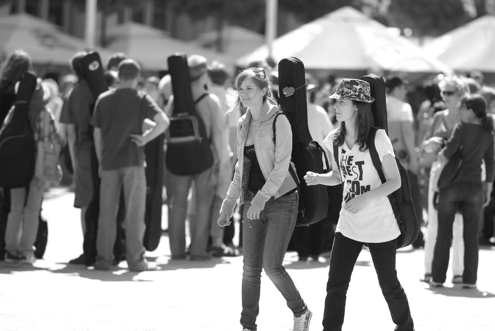 Two musicians carry guitar cases through a crowd on their way to travel.